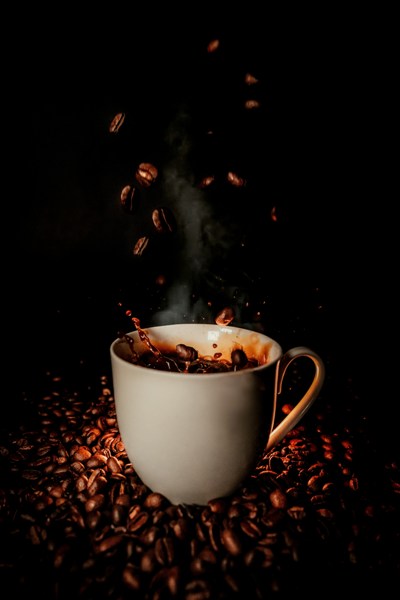 A cup of steaming coffee on beans